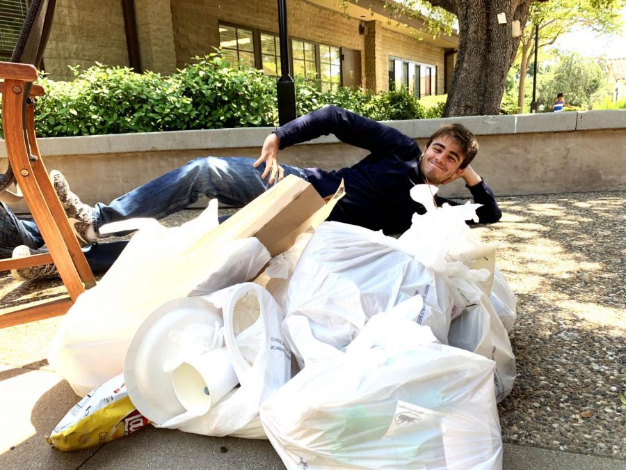 JP Calderoni (‘19), a former Honors Global Sustainability & Solutions student, poses next to the aftermath of the Environmental Club’s campus clean-up. Photographed by Emma Lin (‘20).