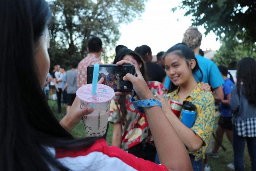 VWS students smile with their intricate face paint designs on display for their friend, who has an iPhone snapping a photo in one hand and a cup of Ding Tea boba in the other. 