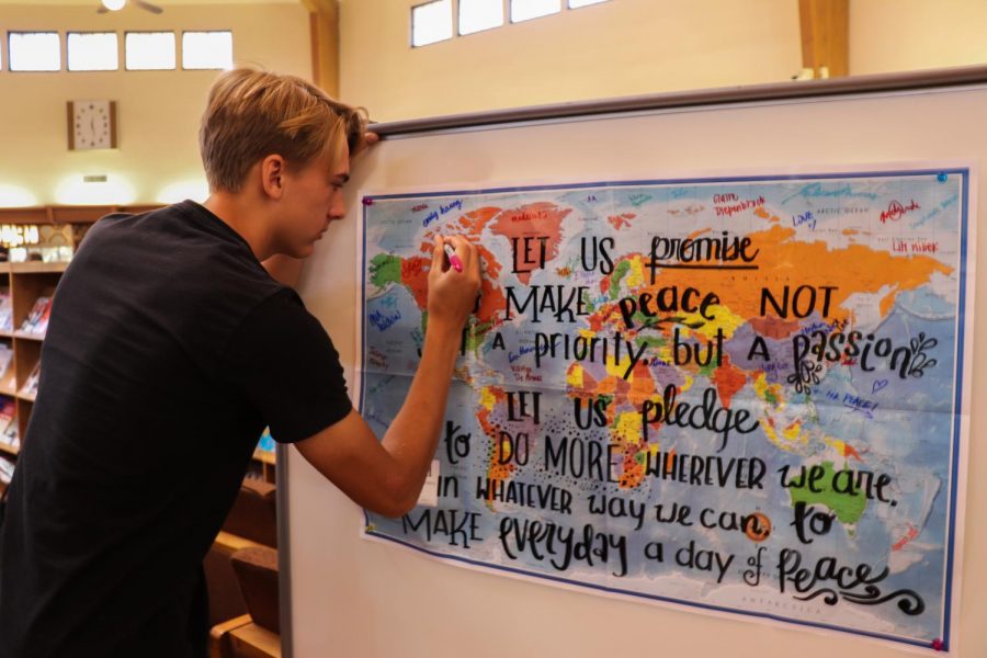 Ethan Caldecott (‘21) signs his name on the world map, taking the peace pledge.