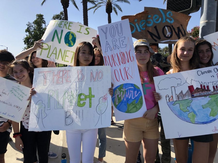 Students hold posters they made from recycled materials during the Rancho Cucamonga climate strike. 