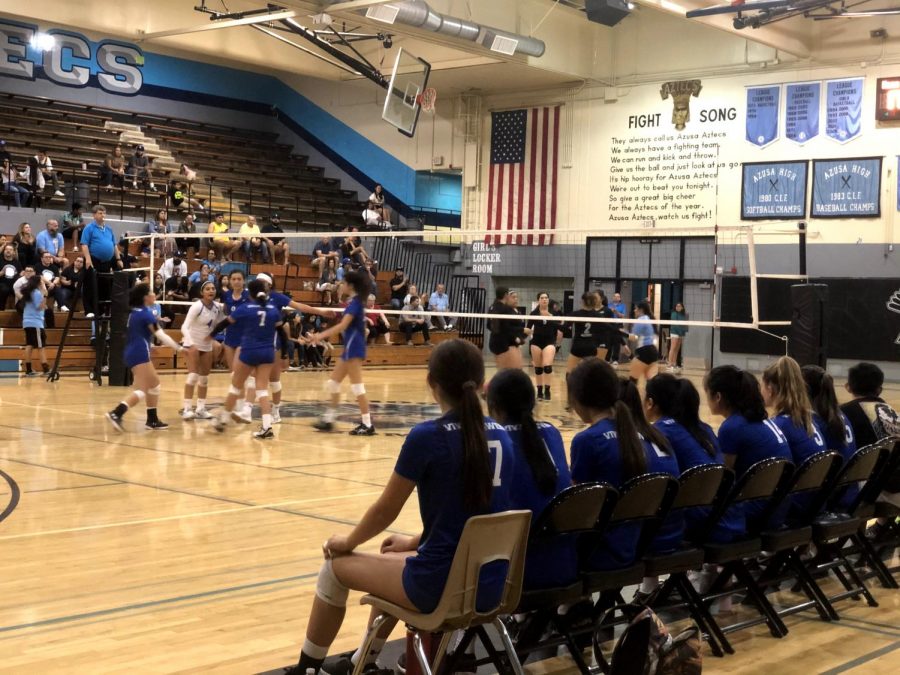 Bench players observe the point from the sidelines.