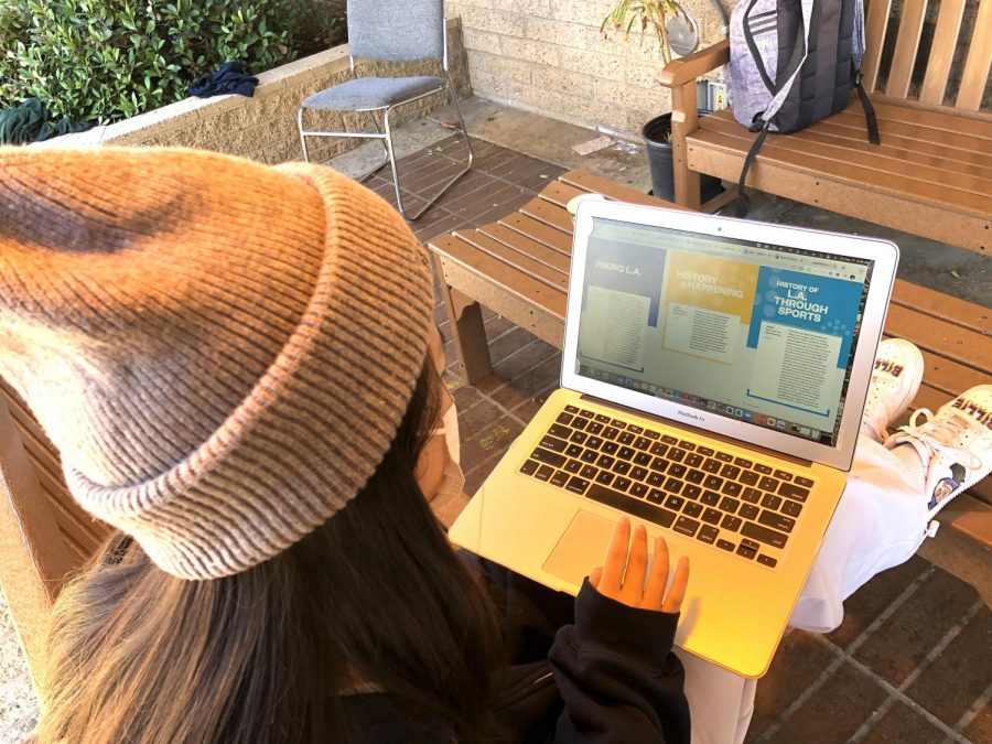 Emily Wang ('22) sits on the senior bench outside Fawcett Library while reading through the 2022 Unbounded Catalogue. She looks through all the different courses offered this year to find the ones that appeal to her most.