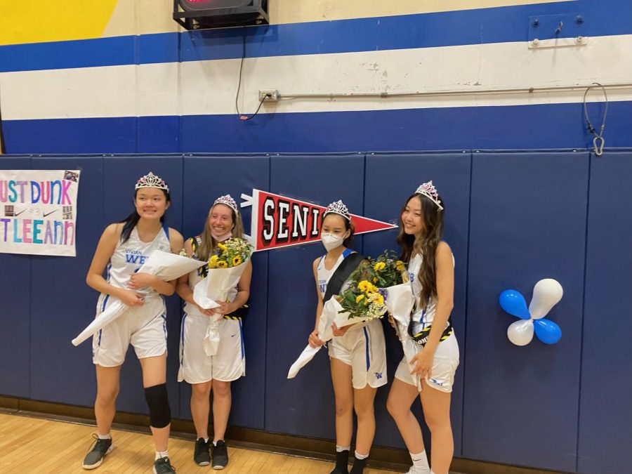 The team’s senior players, (pictured from left to right) Leeann Shu (‘22), Bianca Arteaga (‘22), Marie Blake (‘22), and Allison Paik (‘22), pose next to a banner following the incredibly close, yet gratifying game. They are wearing crowns and sashes, and holding bouquets that were given to them by their team members.  