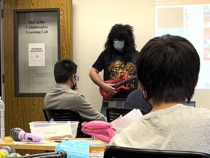 Students watch a musical performance from “Brian May” (Nick Protich), the legendary lead guitarist of rock band Queen. Throughout the unbounded course, young technicians worked to save Brian May, and the whole world, from a terrible fate. 