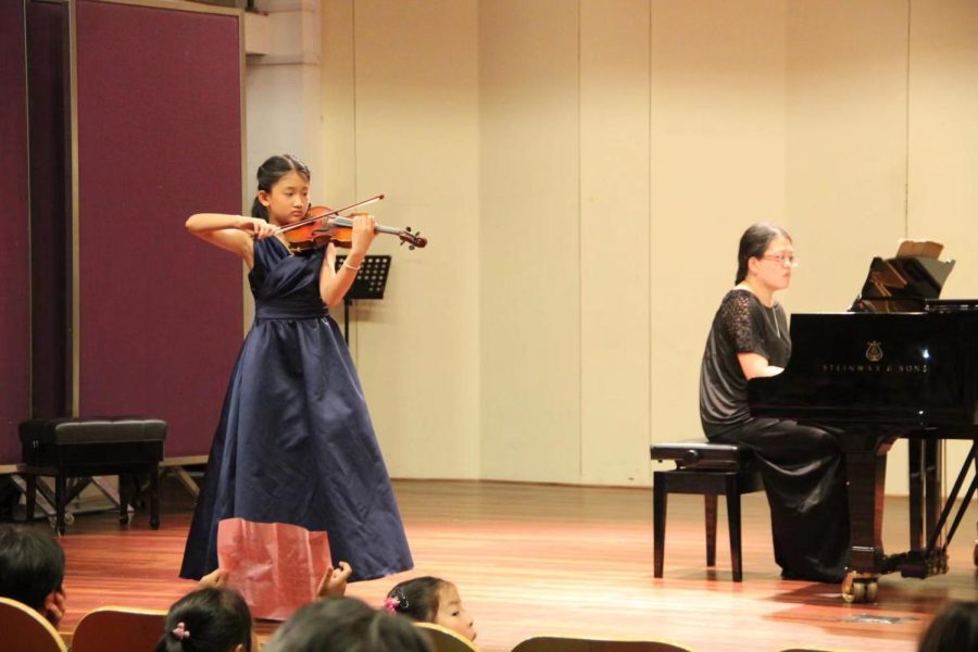 Jessica Cao (‘23) plays the violin in a concert as the crowd watches admiringly. 
