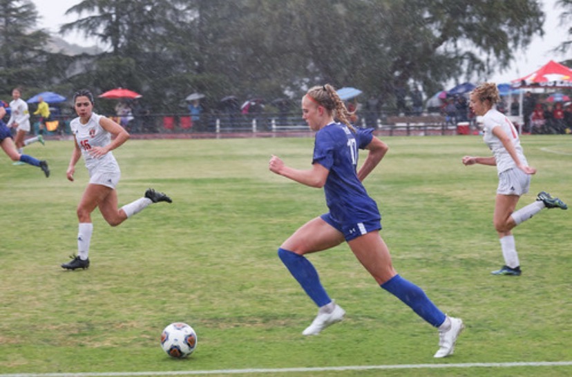 Abbey Cook (‘23) kicks the ball down the field during the rainy state finals game.  