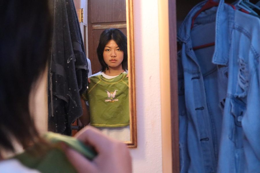 Jolina Zhao (‘23) gazes into her mirror in South Hutch holding a green crop top. Every morning, boarders must choose an outfit from their clothing options located in a closet with limited space. Though students bring items of their liking to their dorms, choosing an outfit that fits Webb’s dress code can limit the self-expression for some students who, some days, want to be comfortable or wear a specific item. “Sometimes, I just wear a long shirt to cover my sweat shorts because I want to stay comfortable,” Jolina said.