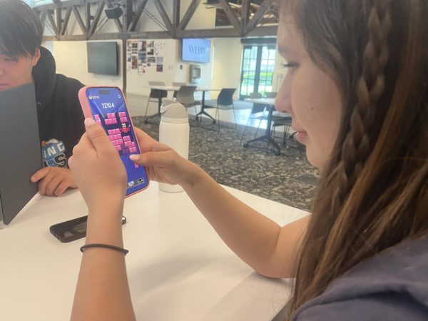 Maya Chin (‘26) plays Block Blast on her phone during her free block in Stockdale Community Center. Block Blast is a mobile game similar to Tetris and has two game modes. "I think a lot of people play [Block Blast], but I don't know how many people are willing to admit it,” Maya said. “Since I’ve downloaded it and brought it up to other people, I’ve seen them also download and play it. I’ve seen some crazy high scores which are not healthy; they probably spent at least 3 hours trying to get it.” 
