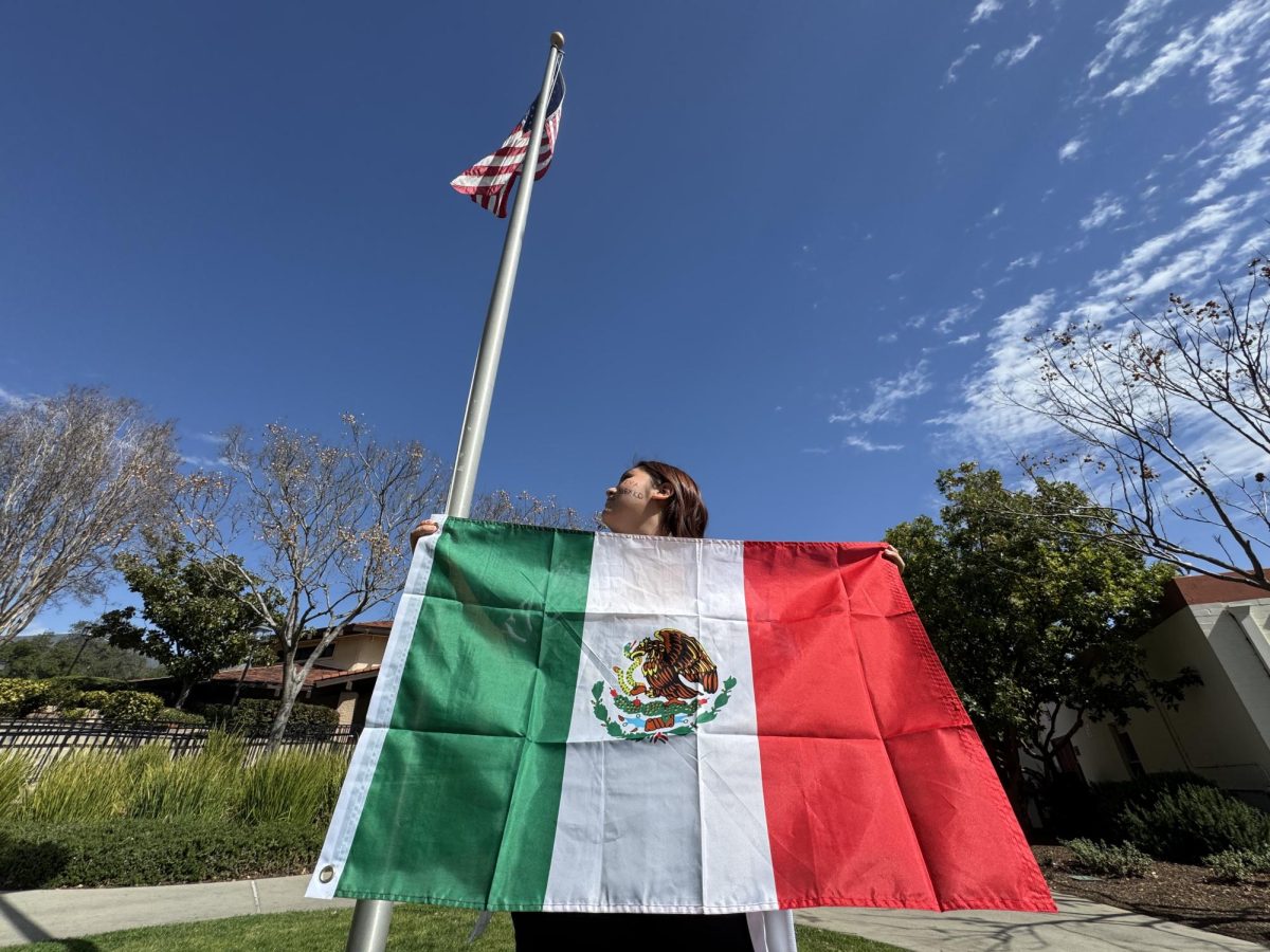 Ash Cortéz ('28) stands in the Quad, holding the Mexican flag as she looks up at the American flag towering above her—a moment that reflects the complex emotions surrounding immigration policies and national identity. “The protests had a profound impact on me—they brought me down at times, but they also inspired me. I wanted so badly to be there, to be out in the streets, actively supporting the cause” said Ash Cortéz (‘28).  This quote shows Ash's struggle, feeling both discouraged by the challenges her community faces and inspired by the protests.  